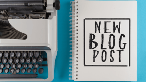 A typewriter next to a notebook that has 'New blog post' written on the front.